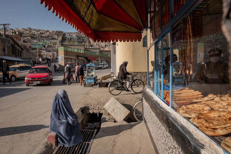 Een vrouw bedelt aan een bakkerij in Kabul